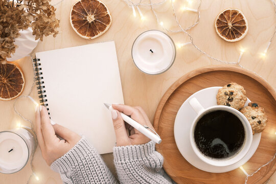 Back to life, goal list concept. Woman's hand writing in empty notebook on wooden table. Resolutions, plan, goals, checklist, idea concept. Top view, flat lay, copy space. 2022. Christmas, New Year