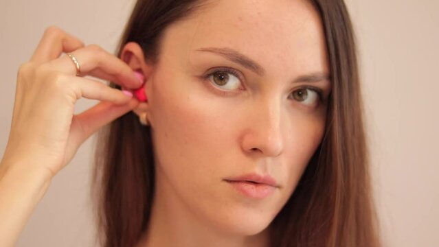 Young woman shows how to correctly insert earplugs into noise protection.