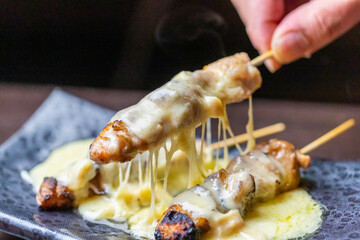 焼き鳥にチーズをかけて食べる