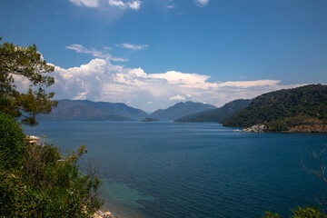 Fototapeta premium Beautiful nature, sea, mountains and forests. Sunny day. Green trees. Blue colorful sky. A beautiful summer day. Beautiful sea water.