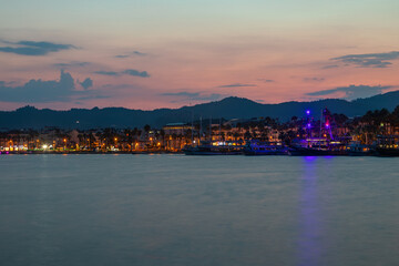 Beautiful and colorful sunset on the sea. Small sea town. Beautiful sky and mountains. Calm summer evening.