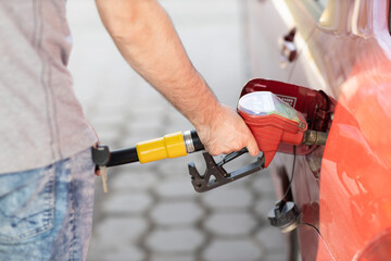 Fototapeta na wymiar Man filling fuel tank in his hand at gas station.