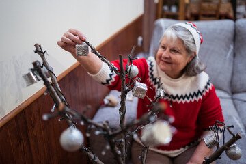 Senior woman decorating leafless tree