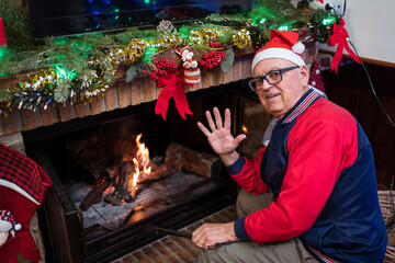 Senior man in Santa hat near fireplace