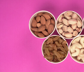 A variety mix of dried fruits and nuts on a pink background. Selective focus.Concept of Healthy fitness super food.