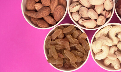 A variety mix of dried fruits and nuts on a pink background. Selective focus.Concept of Healthy fitness super food.