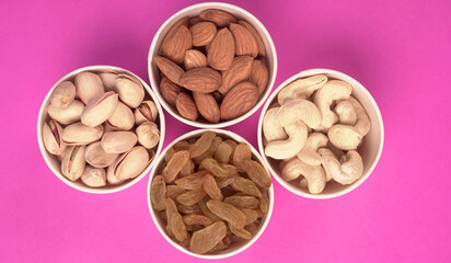 A variety mix of dried fruits and nuts on a pink background. Selective focus.Concept of Healthy fitness super food.
