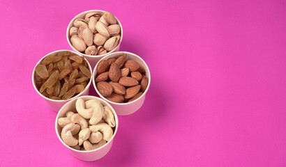 A variety mix of dried fruits and nuts on a pink background. Selective focus.Concept of Healthy fitness super food.