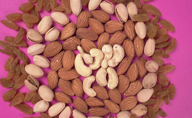A variety mix of dried fruits and nuts on a pink background. Selective focus.Concept of Healthy fitness super food.