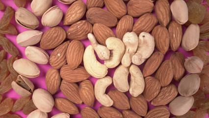 A variety mix of dried fruits and nuts on a pink background. Selective focus.Concept of Healthy fitness super food.