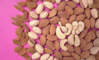 A variety mix of dried fruits and nuts on a pink background. Selective focus.Concept of Healthy fitness super food.