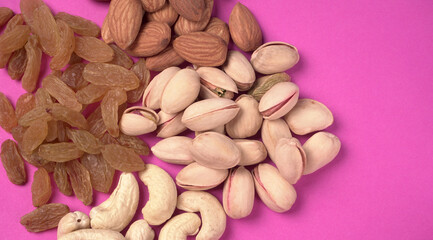 A variety mix of dried fruits and nuts on a pink background. Selective focus.Concept of Healthy...