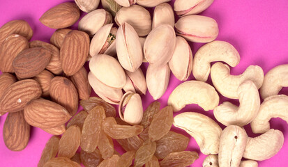 A variety mix of dried fruits and nuts on a pink background. Selective focus.Concept of Healthy fitness super food.