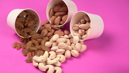 A variety mix of dried fruits and nuts on a pink background. Selective focus.Concept of Healthy fitness super food.