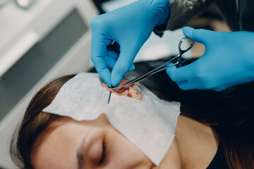 Young woman doing ear piercing at beauty studio salon