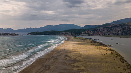 Long sandy beach. Sand braid. Sea and river. The mountains. Strong waves on the sea. Clouds in the sky. Beautiful nature.