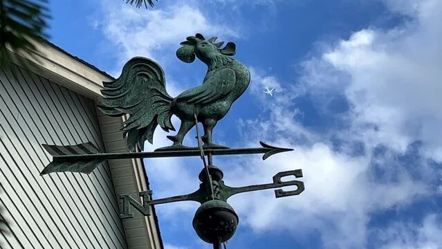 a cockerel that indicates where south is north and also shows the direction of the wind sits on the roof of the house he has iron arrows And an airplane flies over him. High quality 4k footage