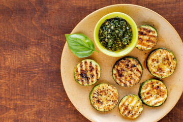 Grilled zucchini  slices with homemade rustic style chopped basil leaves pesto sauce in a bowl.