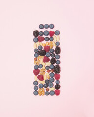 Nuts and berries in shape of a battery on pastel background. Full energy concept. Healthy snack.