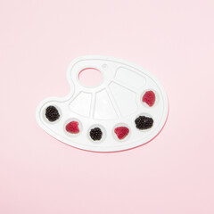 Palette with raspberries and blackberries on pastel background. Summer fruit concept.