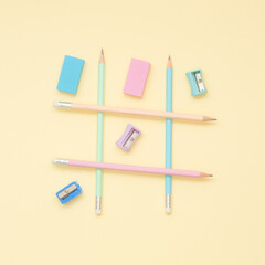 Tic tac toe game with pencils, erasers and sharpeners on pastel background. School is fun concept.