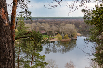 Obraz premium Spring view through pine trees on riverside with recreation area. Cossack mountain, Korobovy Hutora (Koropove village) on Siverskyi Donets River in Ukraine