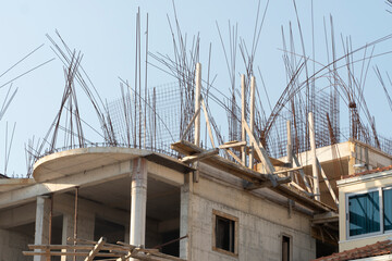 steel reinforcement sticking out of a concrete unfinished building on a construction site.