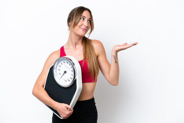 Young caucasian woman isolated on white background with weighing machine