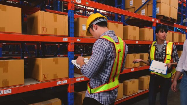 Asian man stocking up with barcodes on a box placed on a steel shelf and Business man checking stock with female staff giving details in warehouse