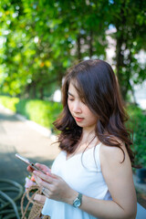Fototapeta na wymiar Beautiful asian women use smartphone in city green park outdoor recreation relax in city park