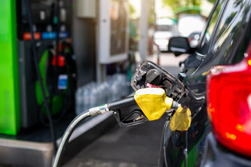 Selective focus to old red fuel nozzle with blurry fuel dispenser in gas station.