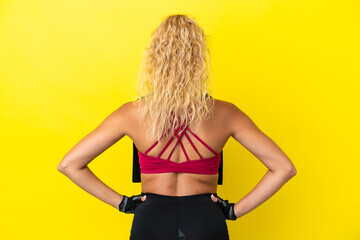 Sport woman with towel isolated on yellow background in back position