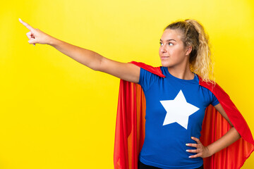 Girl with curly hair isolated on yellow background in superhero costume with proud gesture © luismolinero