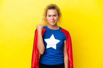 Girl with curly hair isolated on yellow background in superhero costume