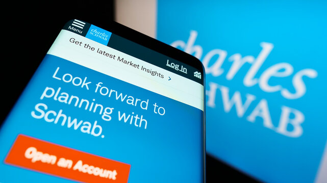 Stuttgart, Germany - 01-06-2022: Mobile phone with website of US financial company The Charles Schwab Corporation on screen in front of logo. Focus on center of phone display.