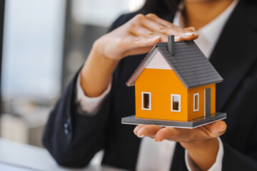 Real estate concept, businesswoman holding a house model, Property insurance and security concept.