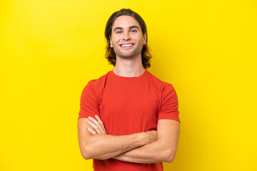 Caucasian handsome man isolated on yellow background keeping the arms crossed in frontal position