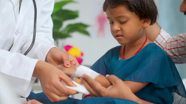 close up shot Doctor hand tying bandage to worried kids injured hand while with caring father at hospital - concept of medicare, childhood mischief and medical first aid.