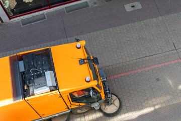 Top above view of small sweeping vacuum cleaner machine equipment removing dust rubbish city street...