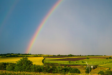 Rainbow over stormy sky. Rural landscape with rainbow over dark stormy sky in a countryside at summer day.