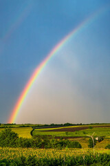Rainbow over stormy sky. Rural landscape with rainbow over dark stormy sky in a countryside at summer day.