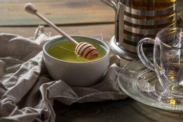 Herbal mint tea cup Transparent glass dark background wooden table still life honey bowl metal kettle teapot spoon cozy
