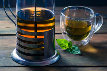Herbal mint tea cup Transparent glass dark background wooden table still life honey bowl metal kettle teapot spoon cozy