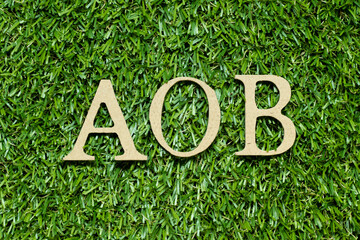 Wood alphabet letter in word AOB (abbreviation of Assignment of benefits or Any other business) on green grass background