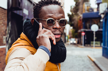 young black man on the street turns to look back talking on the phone