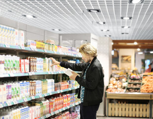  Man choosing frozen food from a supermarket freezer., reading product information