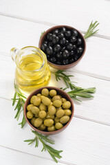 Black and green olives on a white wooden background.