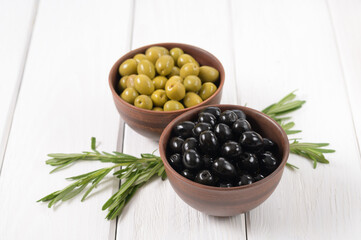 Black and green olives on a white wooden background.