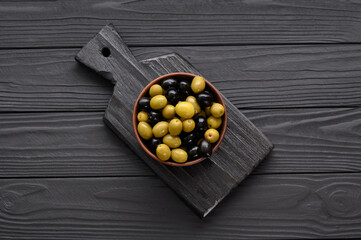 Black and green olives on a dark wooden black background.