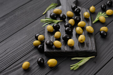 Black and green olives on a dark wooden black background.
